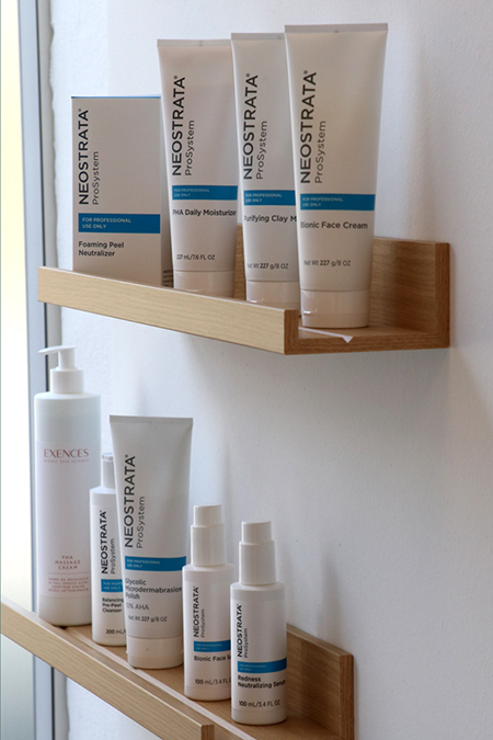 Foto af to små hylder med hudpleje produkter fra NEOSTRATA. Emballagerne er hvide med små blå labels på.